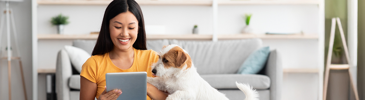 Woman smiling with her dog on her tablet researching audience measurement solutions relevant to audiences.